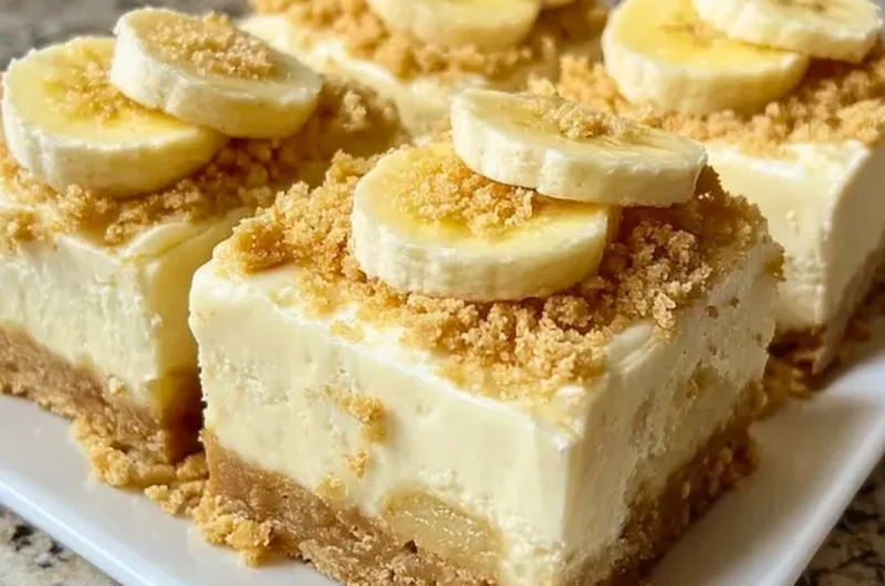 Delicious banana pudding cheesecake squares garnished with whipped cream and bananas.