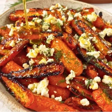 Honey garlic roasted carrots topped with feta cheese on a serving plate