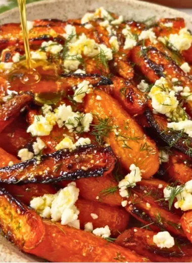 Honey garlic roasted carrots topped with feta cheese on a serving plate