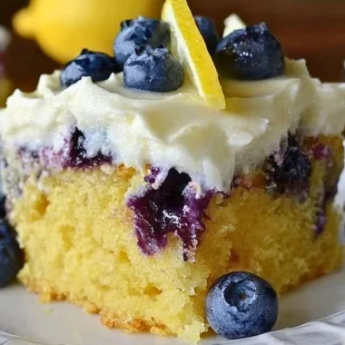 Delicious Lemon Blueberry Poke Cake topped with whipped cream and fresh blueberries