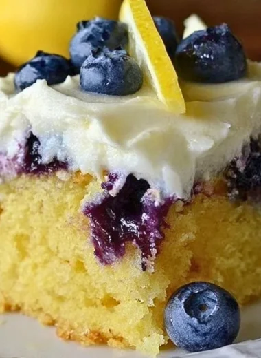Delicious Lemon Blueberry Poke Cake topped with whipped cream and fresh blueberries