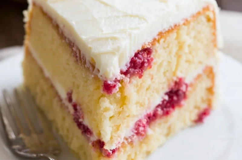 Slice of Raspberry Lemon Cake topped with fresh raspberries and lemon zest