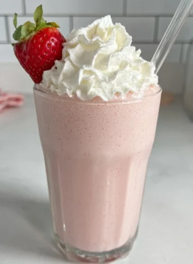 Strawberry protein shake in a glass with fresh strawberries on the side