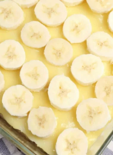 Slices of banana pudding poke cake topped with whipped cream and banana slices