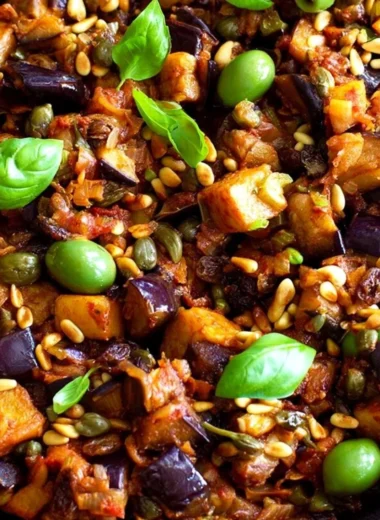 A vibrant bowl of Caponata, showcasing eggplant, tomatoes, and olives.
