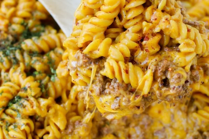 Creamy beef and rotini pasta dish garnished with herbs.