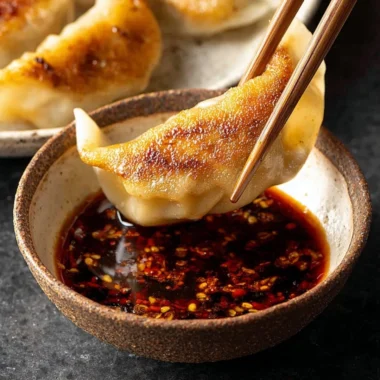 Delicious dumpling dipping sauce in a small bowl with dumplings.