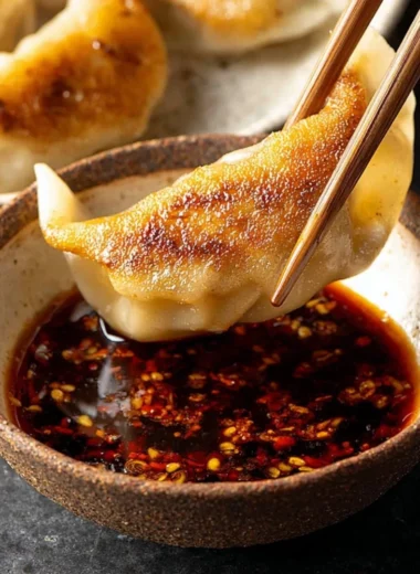 Delicious dumpling dipping sauce in a small bowl with dumplings.