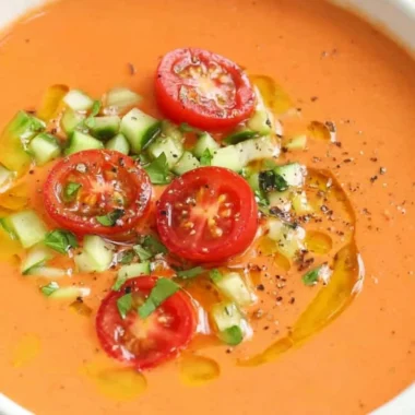 A bowl of easy gazpacho garnished with fresh herbs and vegetables.