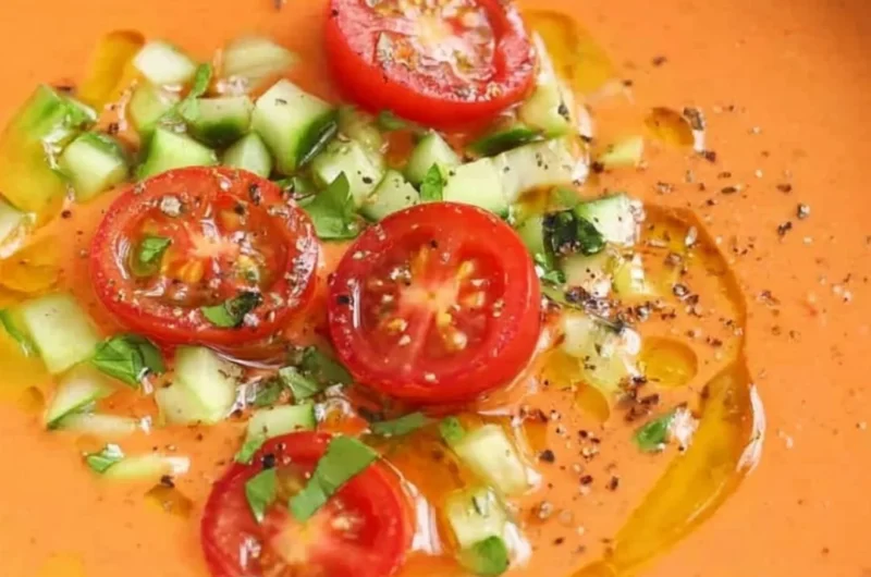 A bowl of easy gazpacho garnished with fresh herbs and vegetables.