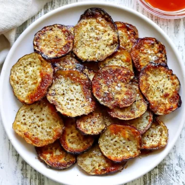 Bowl of crispy homemade eggplant chips served with a dip