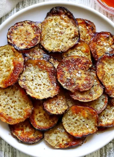 Bowl of crispy homemade eggplant chips served with a dip