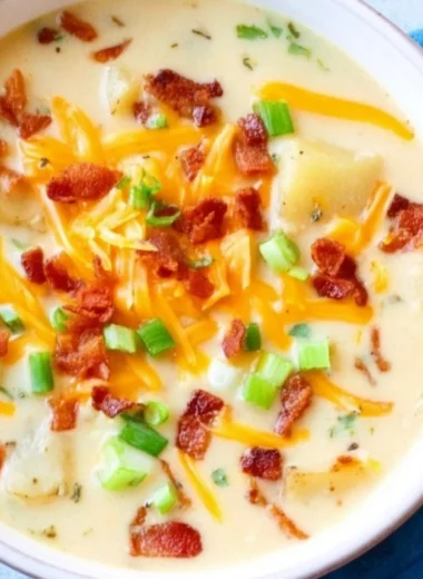 A bowl of creamy slow cooker potato soup garnished with herbs.