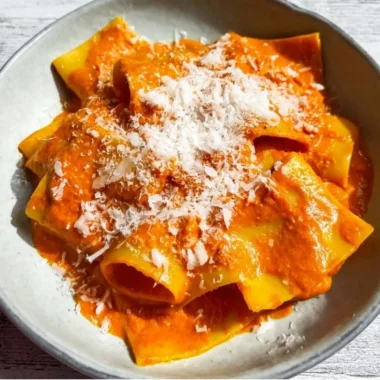 Creamy vodka pasta dish served in a bowl with herbs and parmesan cheese.
