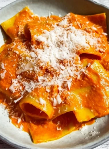 Creamy vodka pasta dish served in a bowl with herbs and parmesan cheese.