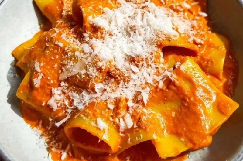 Creamy vodka pasta dish served in a bowl with herbs and parmesan cheese.