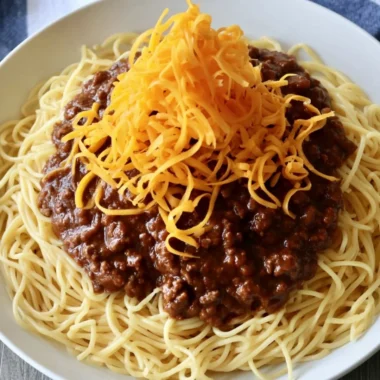 A bowl of Cincinnati Chili topped with shredded cheese and onions