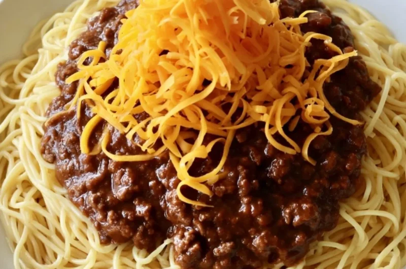 A bowl of Cincinnati Chili topped with shredded cheese and onions