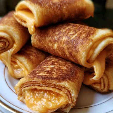 Plate of crispy cheesy roll ups, golden and delicious snacks filled with melted cheese.