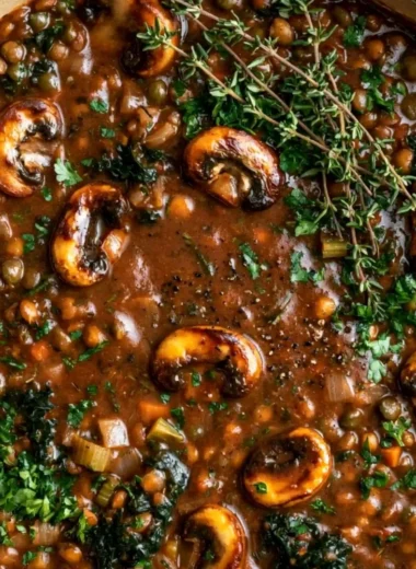Vegan lentil mushroom stew in a bowl, garnished with herbs and spices.